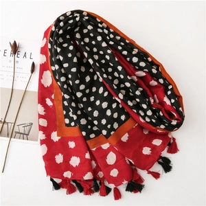 Détail de l'écharpe à pois rouges et noirs avec des franges et des bordures oranges