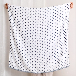 Wide view of white shawl with dark blue polka dots and decorative lace fringe trim