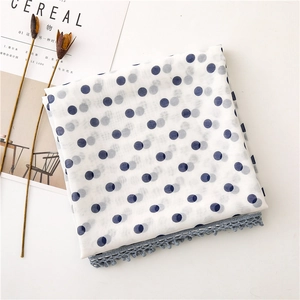 Detail of white semi-transparent scarf featuring blue polka dots and grey lace trim edges