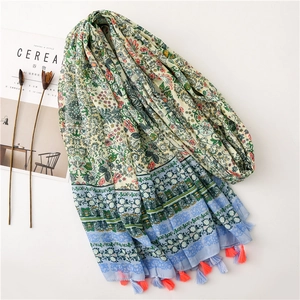 Green cotton linen scarf with floral print and colorful tassels on minimalist background