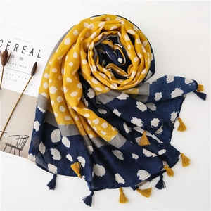 Détail d'une écharpe à motif léopard jaune et bleu marine avec pompons à franges