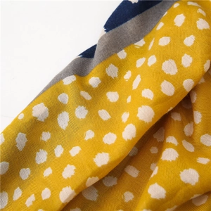 Détail macro d'une écharpe jaune à pois avec texture chevron et ourlet rayé