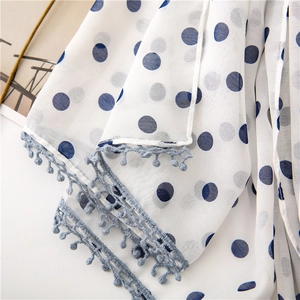 Detail of white chiffon scarf with blue polka dots and light blue pom pom tassel edges