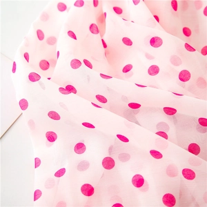 Macro detail of lightweight pink chiffon fabric with vibrant magenta polka dots