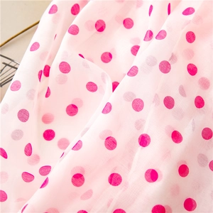 Close-up of light pink sheer chiffon fabric featuring magenta polka dots and soft textures