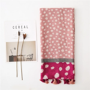Détail de l'écharpe à pois multicolores avec pompons colorés sur tissu en coton lin