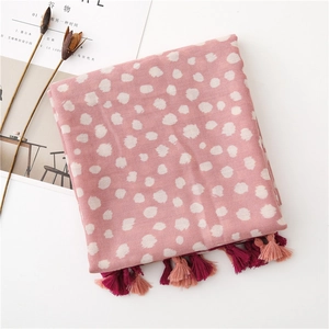 Vue détaillée d'une écharpe rose à pois avec frangée avec une texture tissée douce