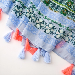 Detail of floral printed linen scarf featuring light blue fringes and bohemian patterns