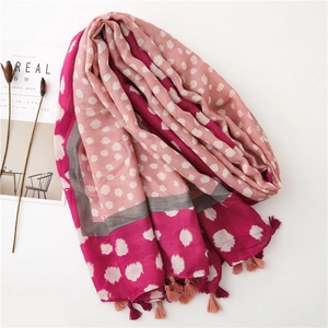 Détail d'une écharpe léopard rose avec des pompons et une texture légère et douce
