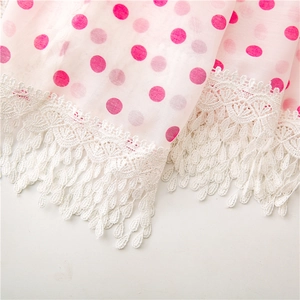 Macro detail of pink polka dot tulle fabric with white lace trim and drop fringe