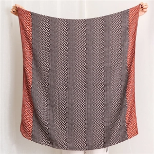 Detail of soft knitted scarf with black white and red herringbone pattern and red edges