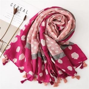 Détail de l'écharpe rose et grise en blocs de couleurs avec pompons et motifs à pois