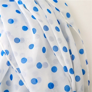Macro shot of white lightweight chiffon fabric with blue polka dots and rolled edges