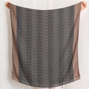 Full view of lightweight shawl featuring black, white, and brown wavy geometric patterns