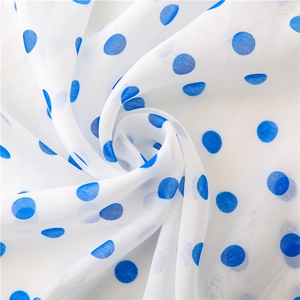 Detail of white chiffon fabric with blue polka dots showing smooth drape and texture