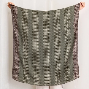 Detail of chevron pattern knit scarf in dark green, brown, and white textured fabric