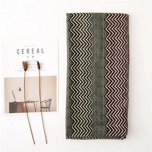 Flat lay of folded herringbone scarf in dark green and brown with lifestyle props