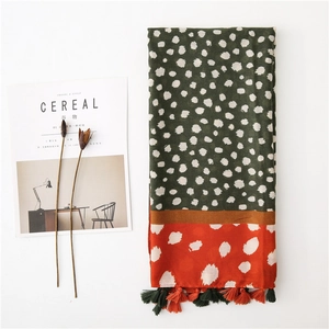 Détail d'une écharpe à pois vert foncé avec panneau orange et bordures à franges