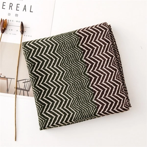 Close-up of zigzag knitted scarf in dark green and brown with lifestyle decor