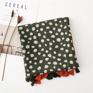 Vue à plat d'une écharpe verte à pois avec pompons bicolores et magazines de style