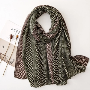 Zigzag pattern scarf in forest green and coffee tones displayed with minimalist props