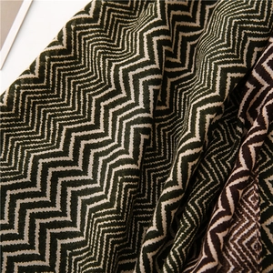 Close-up of zig-zag knitted fabric in dark green, beige, and brown with dense texture