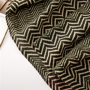 Macro view of woven chevron pattern fabric in dark green and cream white colors