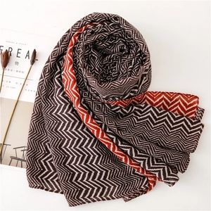 Artistic layout of wavy patterned scarf in brown and brick red next to a magazine