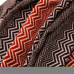 Detail of soft knit shawl featuring a zigzag pattern in orange, brown and beige tones