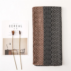 Flat lay of a folded scarf with brown zigzag patterns next to a Cereal magazine