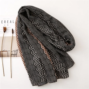 Detail of geometric wave pattern scarf in black brown and cream with a magazine prop