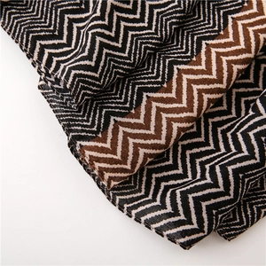 Close-up of zigzag knitted scarf with black, white and brown wavy stripes texture