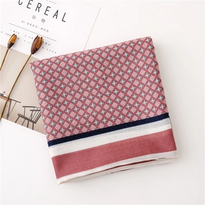 Detailed view of red geometric pattern scarf with striped borders and soft linen texture