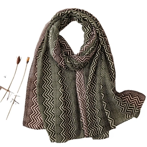 Lightweight woven scarf with dark green and beige geometric wave pattern on white backdrop