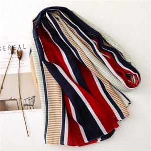 Flat lay of soft striped scarf in navy and red tones next to a lifestyle magazine