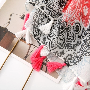 Detail of bohemian floral print scarf featuring pink tassels and soft cotton-linen texture