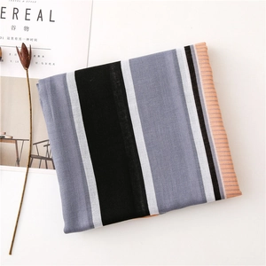 Detailed knit texture of a vertical striped scarf in black, grey, white, and orange hues