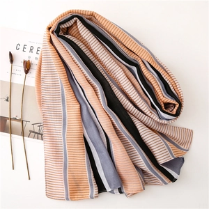 Flat lay of soft orange and grey striped chiffon scarf with artistic dried flowers