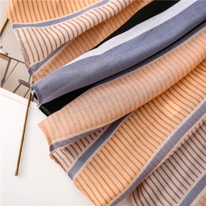 Detail of striped chiffon scarf featuring orange, blue and grey bands with light texture