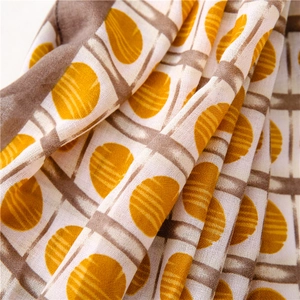 Macro shot of lightweight fabric scarf with yellow polka dots and brown plaid pattern