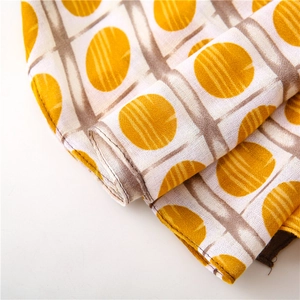Detail of yellow polka dot and brown grid pattern on textured cotton linen fabric