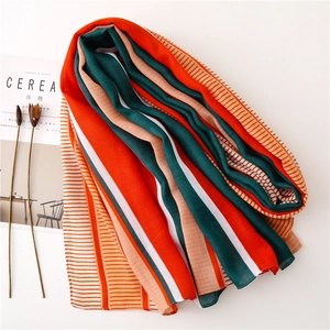 Detailed view of lightweight orange and green striped fashion scarf on white background