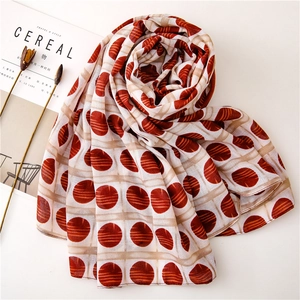 Detailed close-up of cream scarf with red polka dots in an aesthetic flat lay arrangement