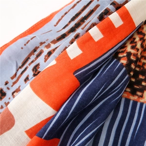 Macro detail of geometric print scarf showing orange and blue woven fabric texture
