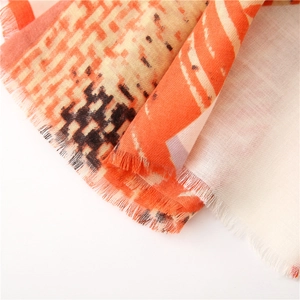 Detail of houndstooth scarf with orange and beige geometric patterns and fringe edges