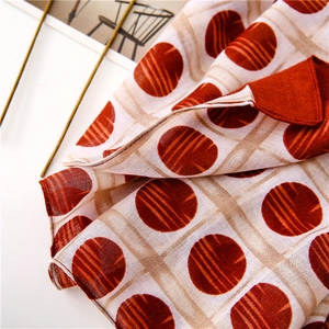 Detail of red polka dots on white checkered cotton linen scarf with elegant accessories