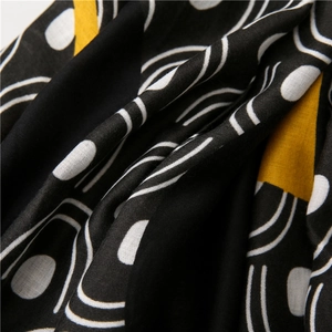 Detail of soft black textile with white geometric patterns and yellow block accents