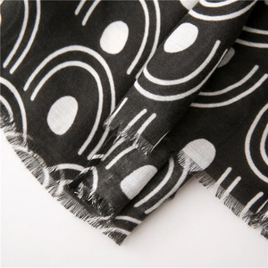 Macro detail of black and white geometric print scarf with soft fringe and woven texture