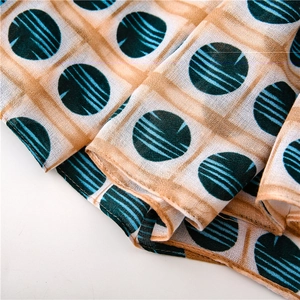 Macro view of khaki woven scarf with green polka dots and light blue striped details