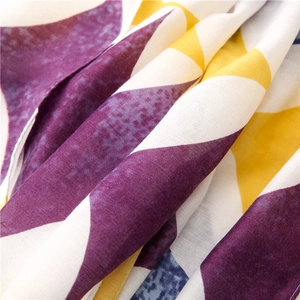 Dettaglio ravvicinato del tessuto con stampa geometrica a triangoli viola e gialli
